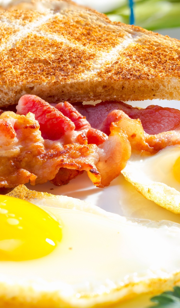 Яичница, бекон и гренки на завтрак на столе 