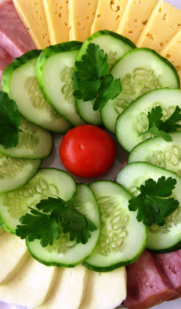 Сыр нарезанный, огурцы и ветчина на тарелке 