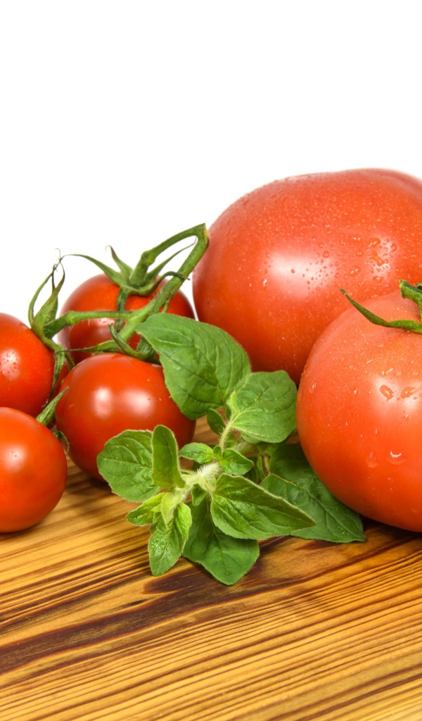 Маленькие и большие помидоры на деревянной доске 