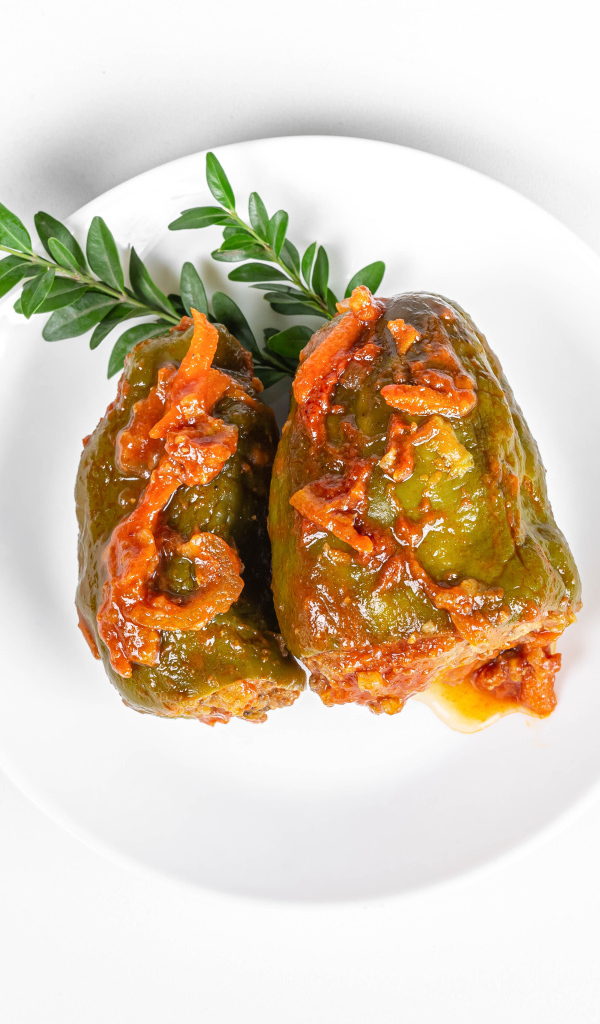 Фаршированный перец на белой тарелке со столовыми приборами