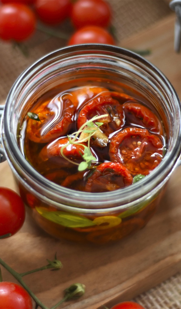 Вяленые томаты в масле в стеклянной банке на столе