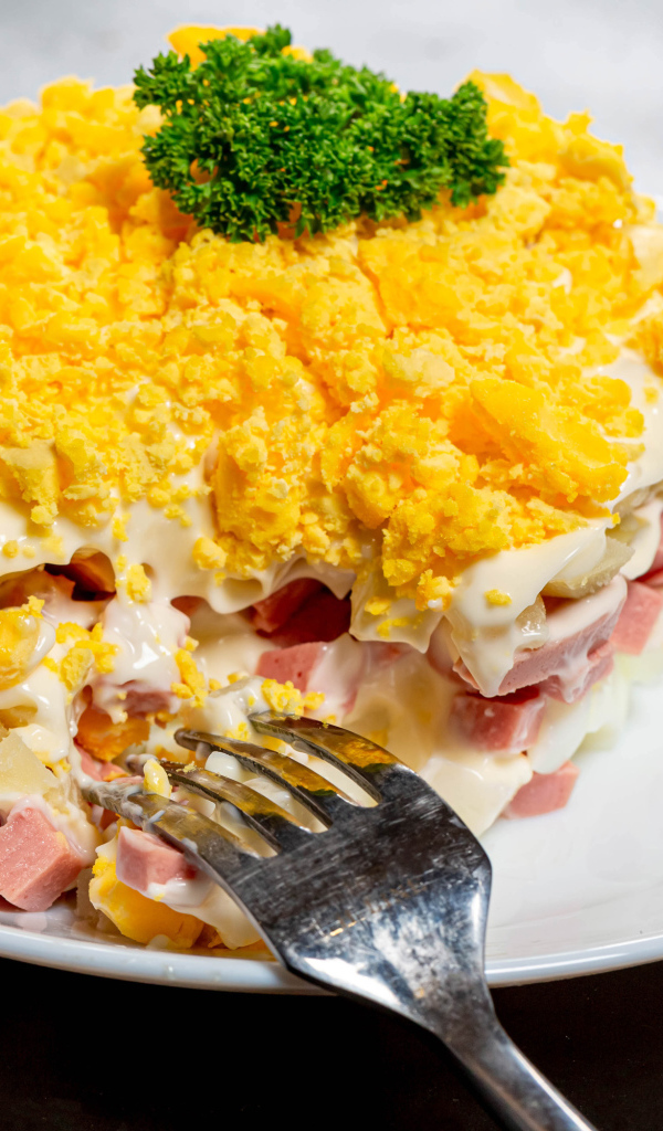 Вкусный салат на белой тарелке с вилкой