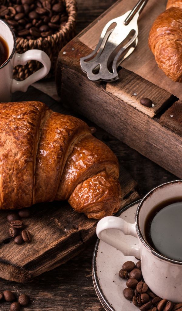 Две чашки кофе на столе с рогаликами и зернами 