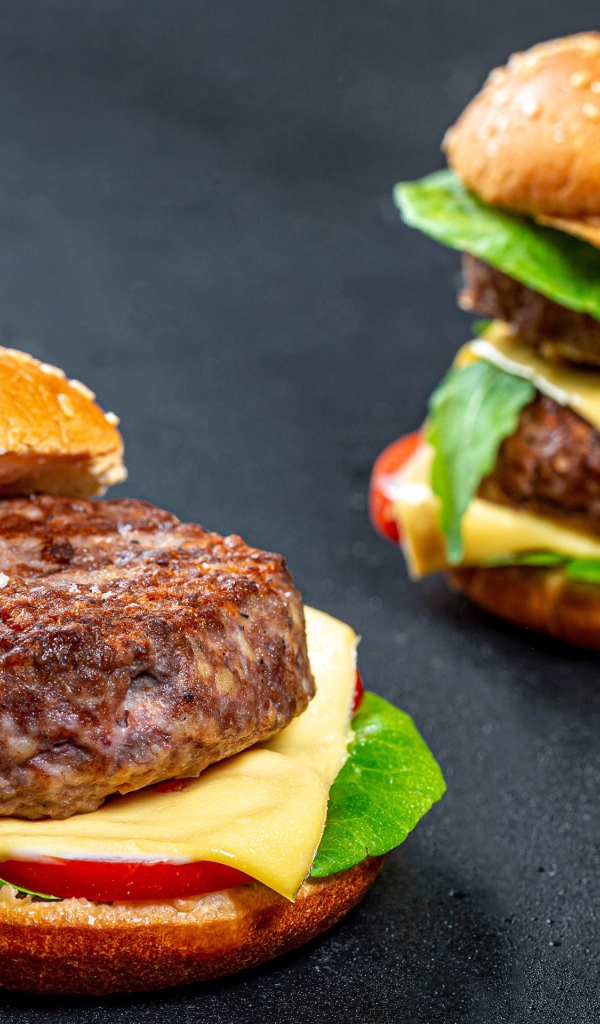 Два аппетитных гамбургера с сочной котлетой на сером фоне