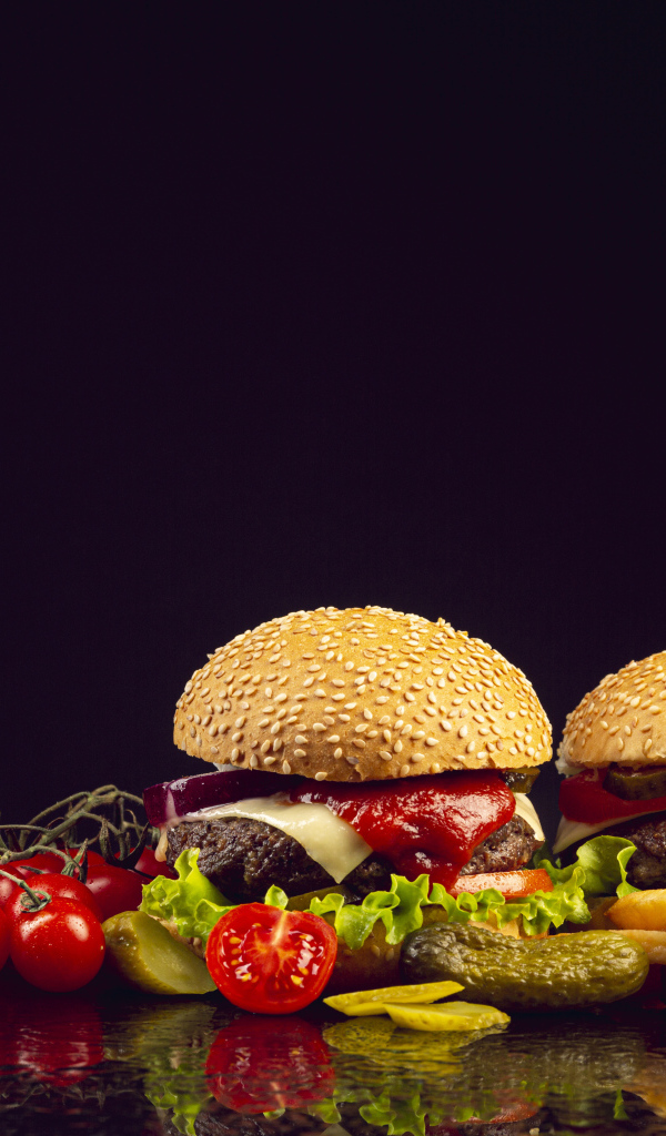 Два гамбургера на столе с ножом, овощами и кетчупом 