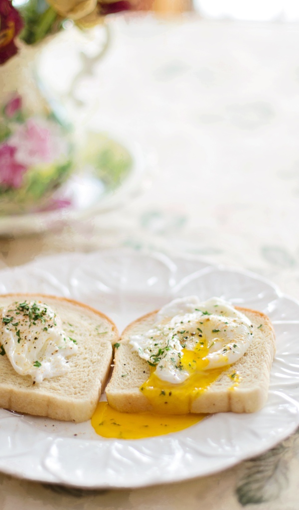 Два куска хлеба с яичницей на белой тарелке на завтрак 