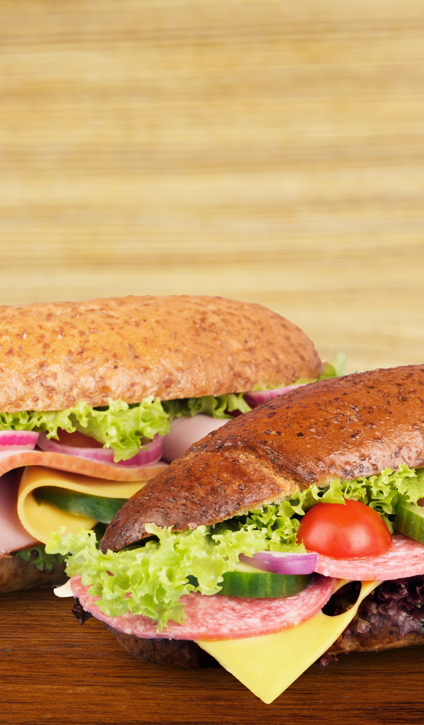 Два вкусных бутерброда с овощами и колбасой на столе 