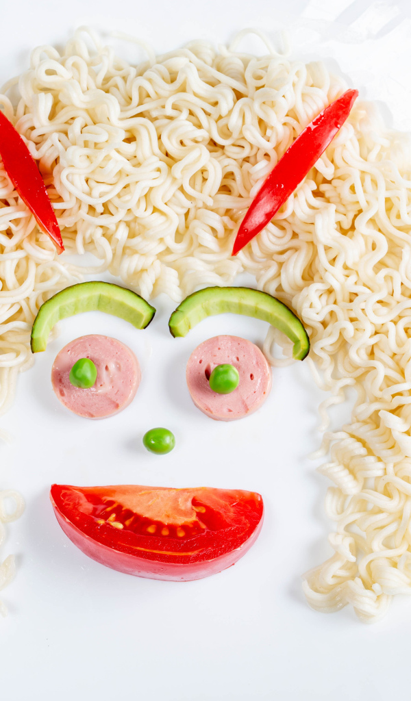 Лицо из вермишели с овощами и колбасой на белой тарелке 