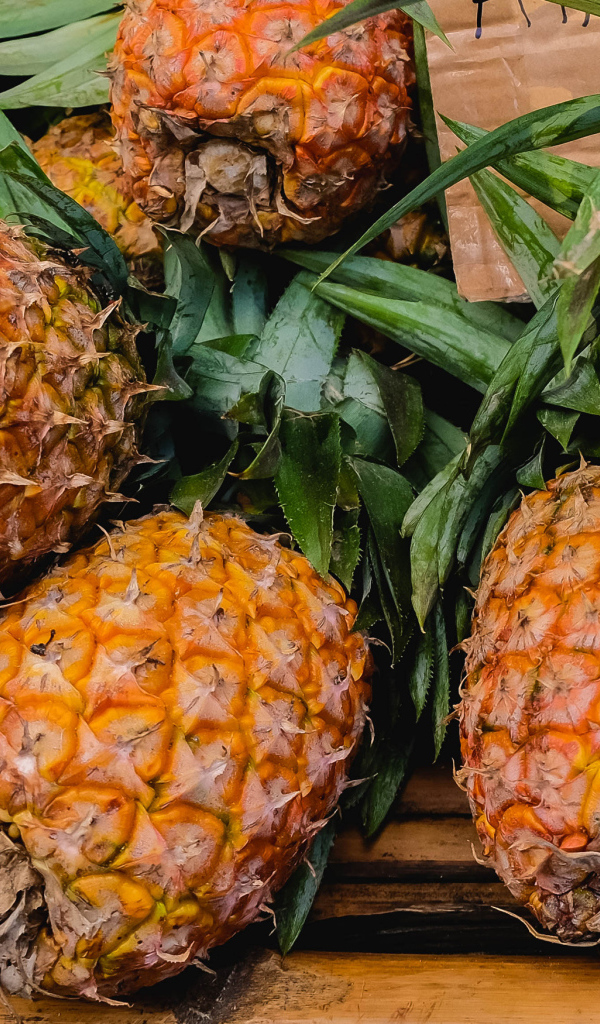 Много больших спелых ананасов на столе 