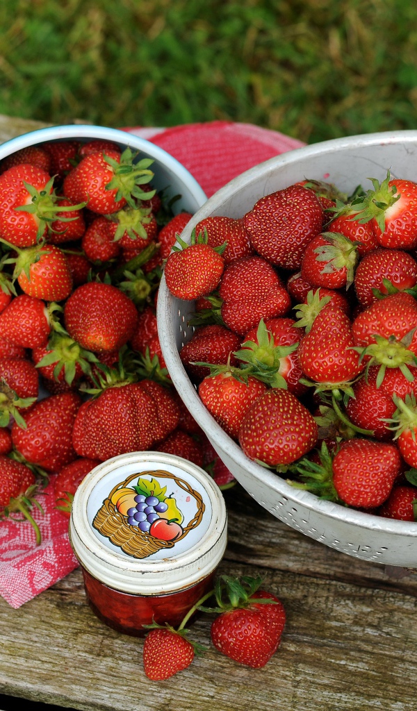 Много спелой ароматной клубники на столе с джемом 