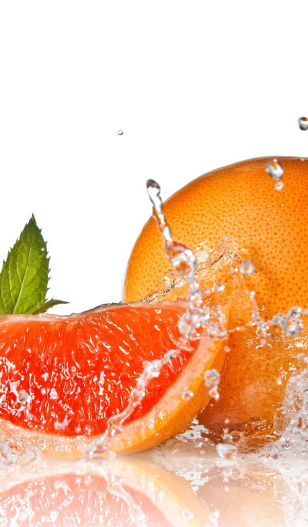 Большой спелый апельсин в брызгах воды на белом фоне