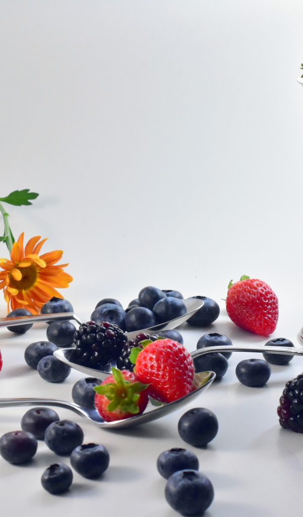 Ежевика, черника и клубника на столе с ложками
