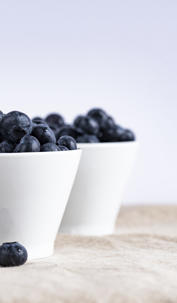 Синие ягоды черники в белой посуде на столе 