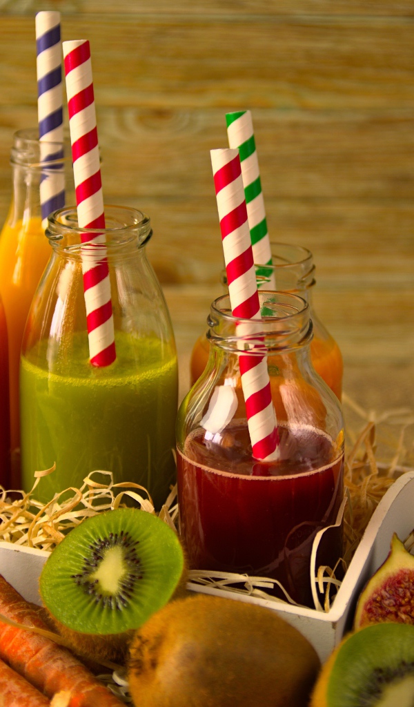 Бутылочки с соком на столе с фруктами 