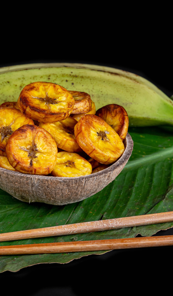 Сушеные бананы на столе с палочками и зеленым листом