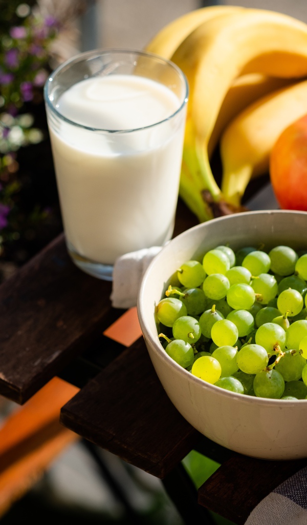 Green grapes on the table with bananas, apples and milk