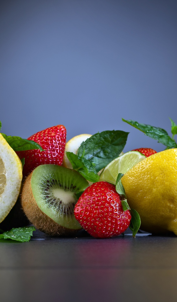 Лимоны на столе с киви и ягодами клубники 