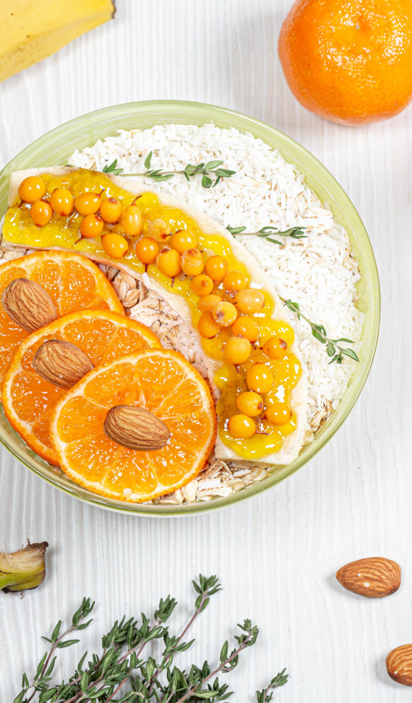 Мюсли с облепихой, бананом и апельсином на столе с фруктами