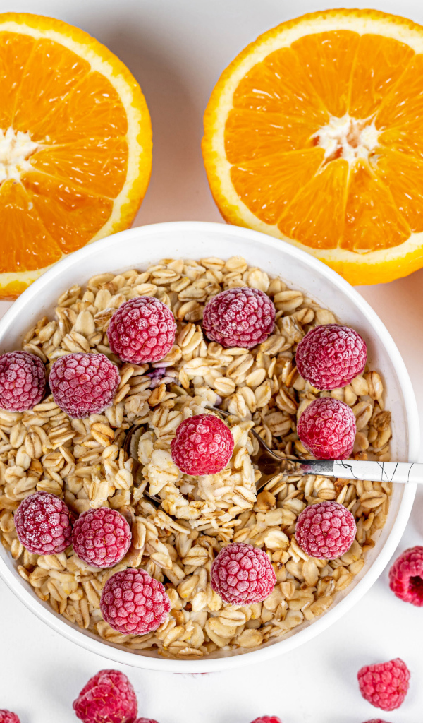 Овсяные хлопья с малиной на белом фоне с апельсинами