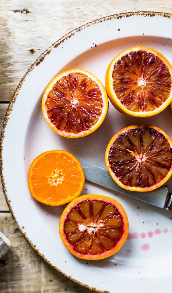 Половинки апельсина на тарелке с ножом