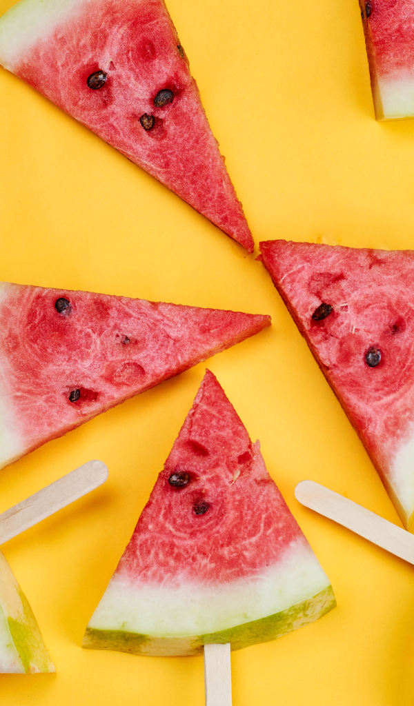 Кусочки арбуза на палочках на желтом фоне