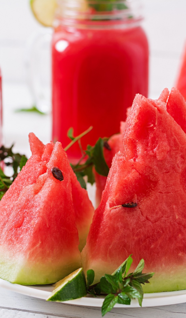 Куски арбуза с мятой на столе с соком 