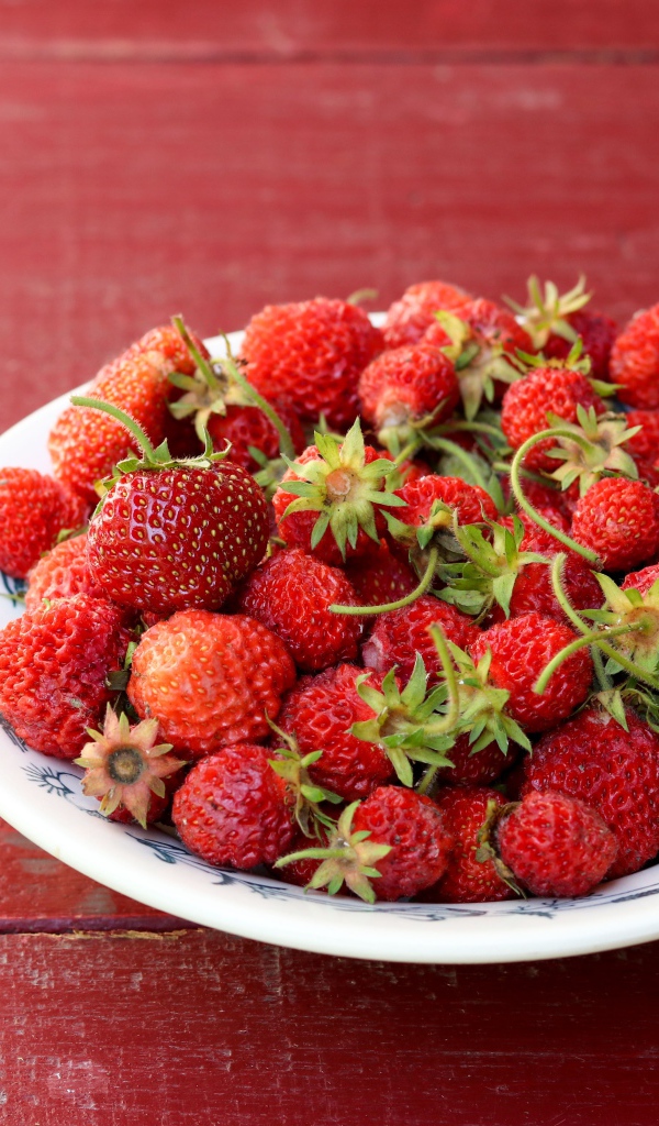 Тарелка со спелой домашней клубникой на столе