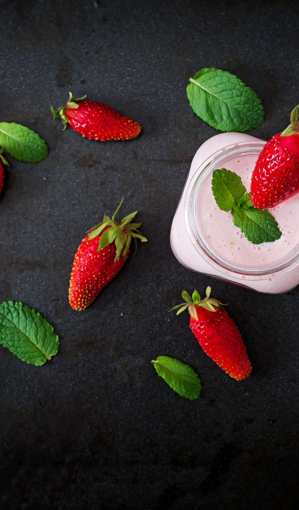 Красная клубника на черном столе с йогуртом