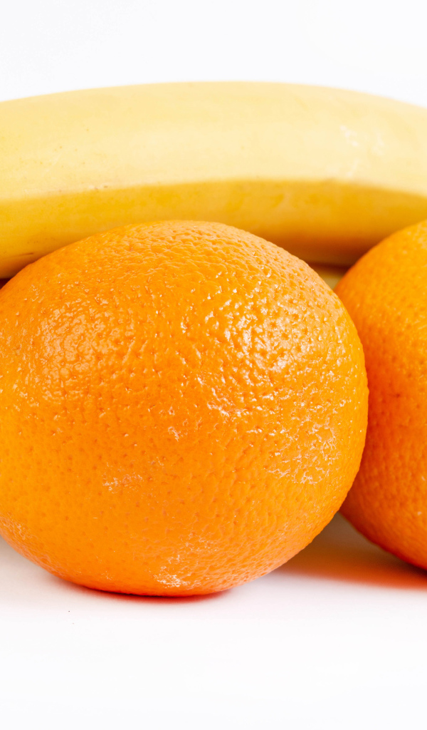 Спелые апельсины и бананы на белом фоне 