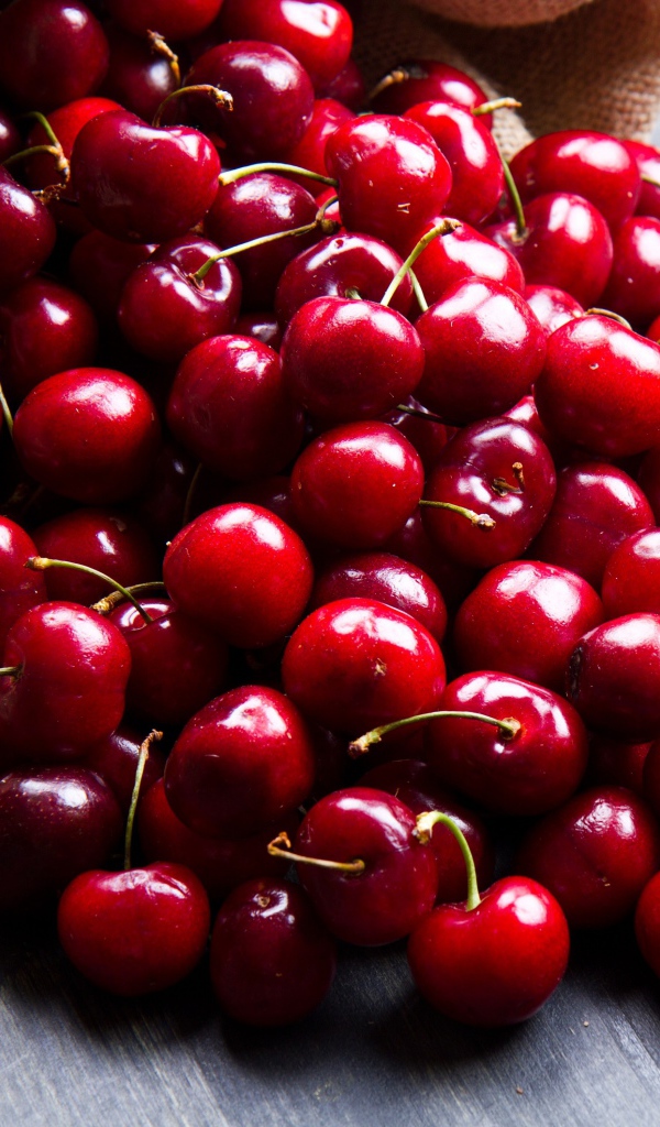 Спелые красные черешни в мешке на столе 