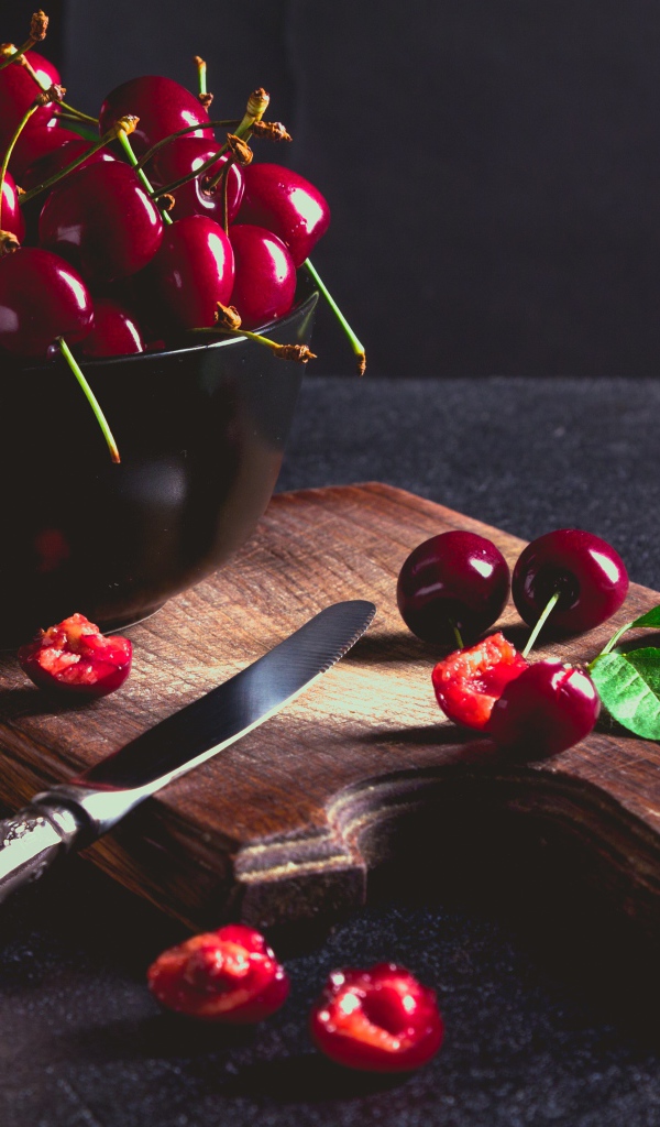 Спелые красные черешни на разделочной доске на столе 