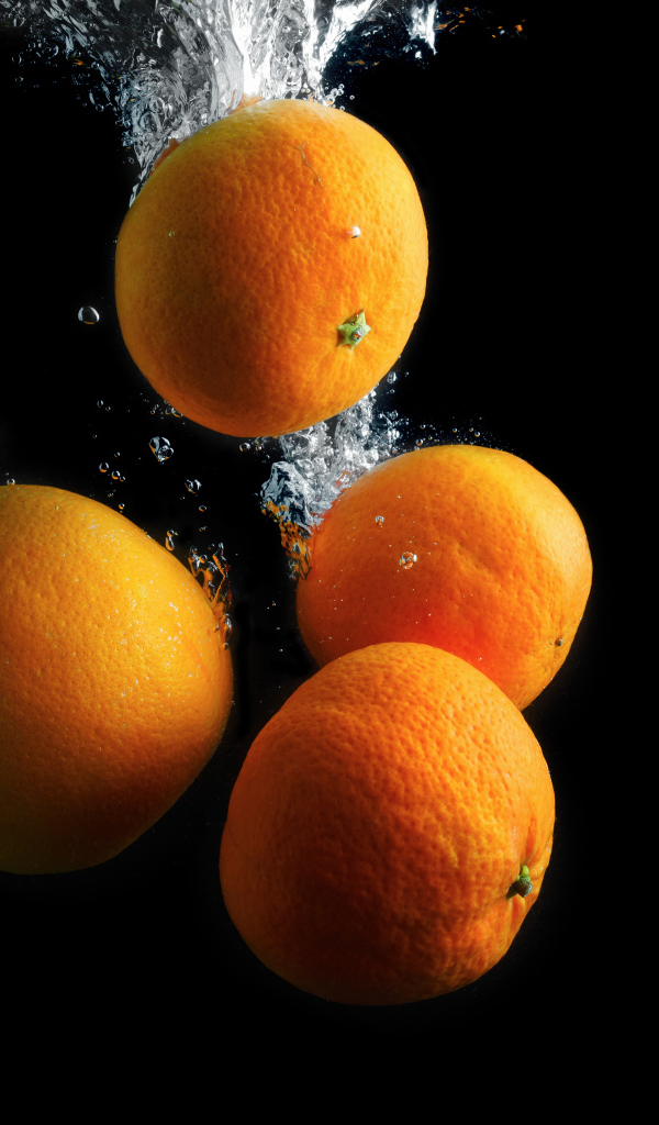 Мандарины и апельсины в воде на черном фоне