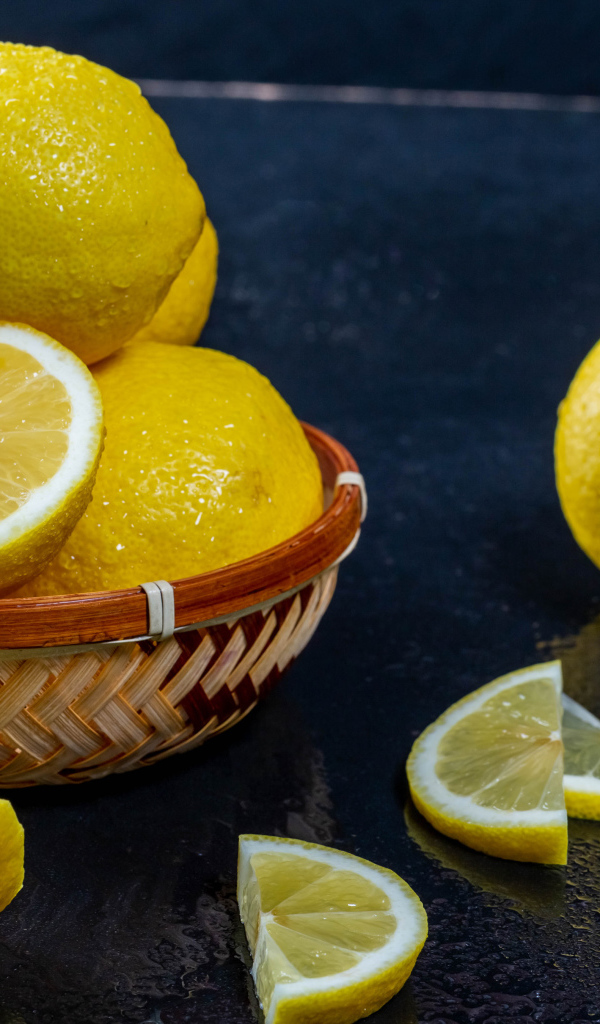 Мокрый лимон с кусочками на черном столе 