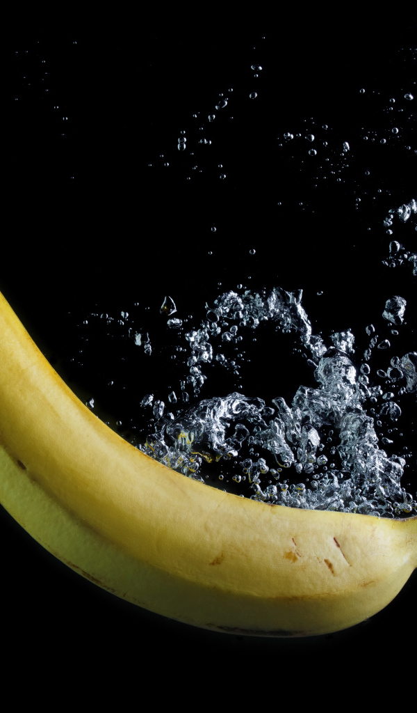 Желтый банан в воде на черном фоне
