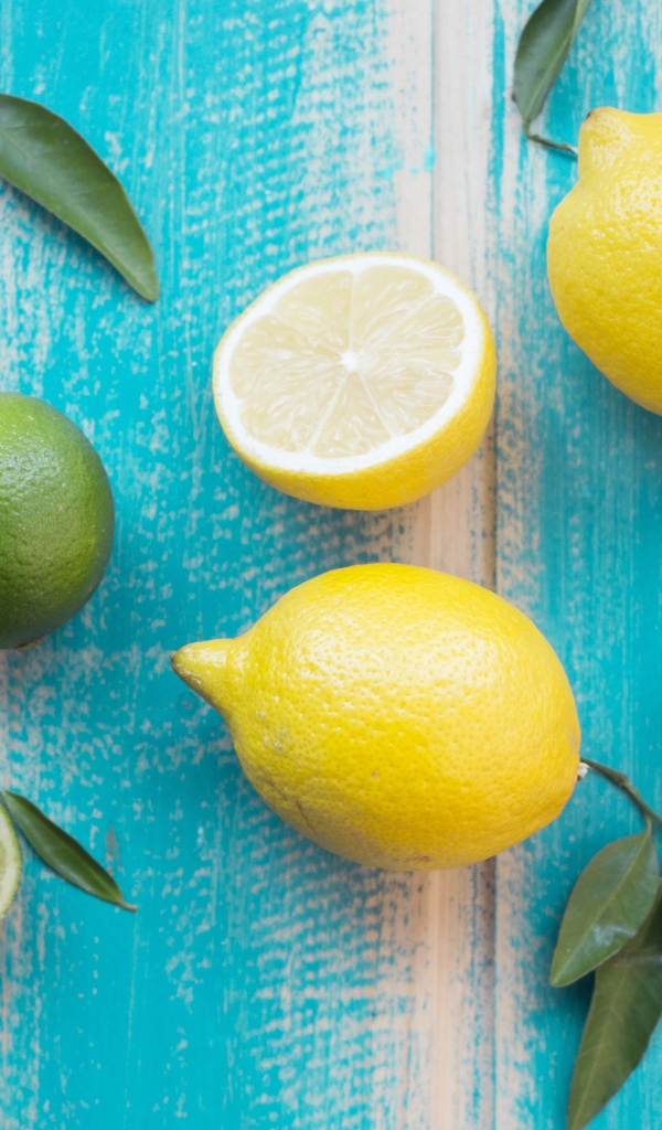 Желтые лимоны и зеленые плоды лайма на столе 