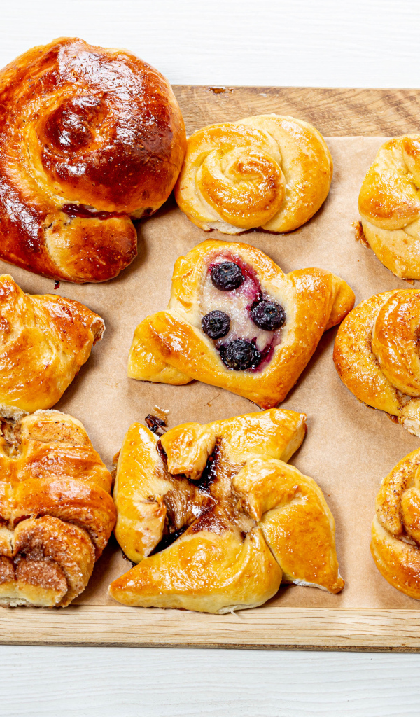 Разная свежая выпечка на доске на белом фоне