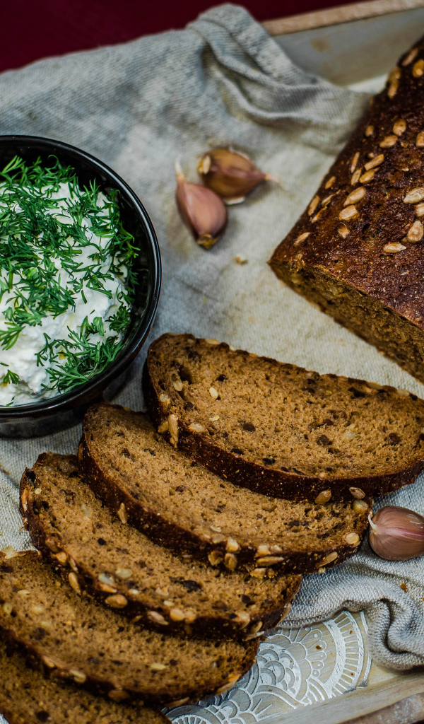 Свежий хлеб с зернами на столе с соусом и чесноком