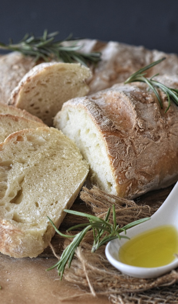 Свежий батон на столе с розмарином и маслом 