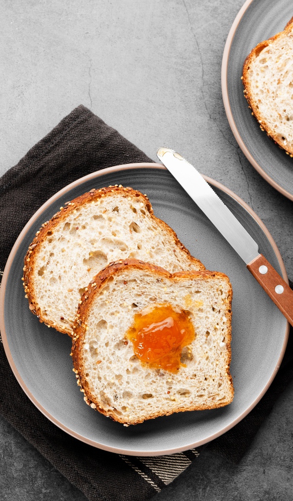 Куски хлеба с джемом на сером столе 