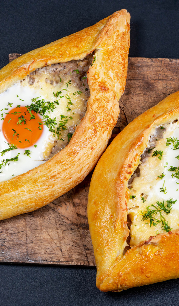 Два больших свежих хачапури с яйцом на доске