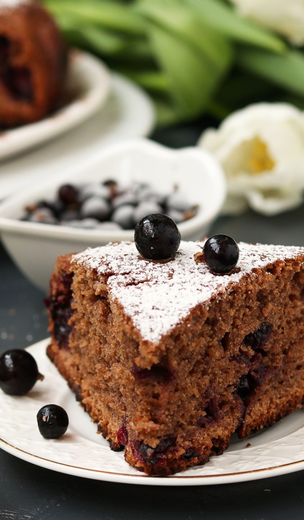 Кусок пирога со смородиной на столе с тюльпанами 