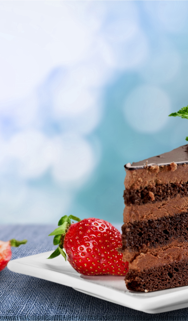 Кусок аппетитного торта с шоколадным кремом и клубникой 