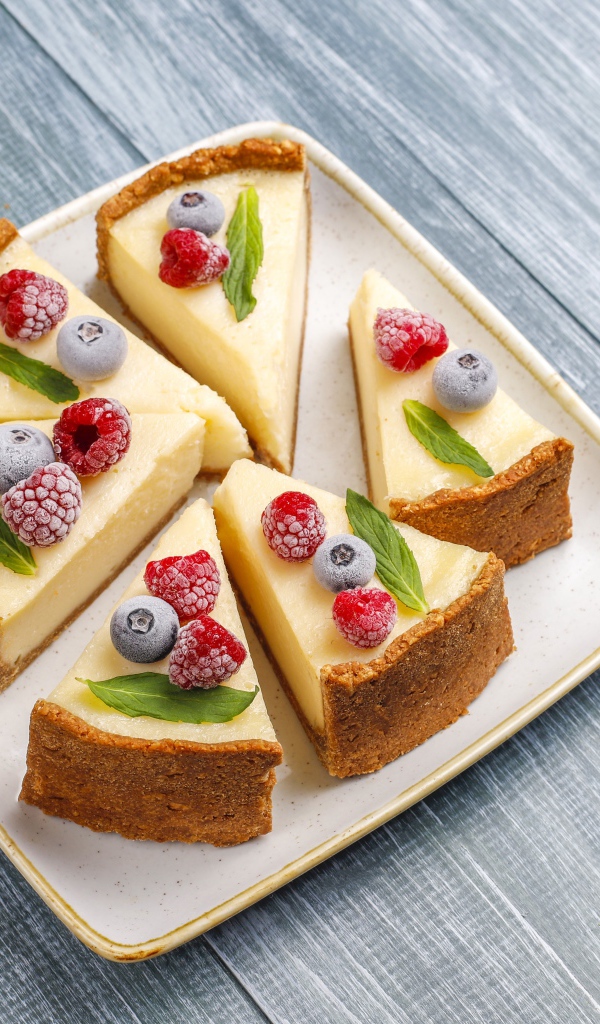 Аппетитный чизкейк с ягодами нарезан кусками на тарелке 