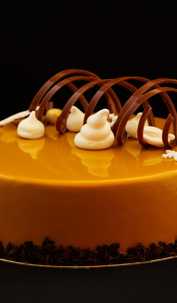 Красивый глянцевый оранжевый торт на черном фоне