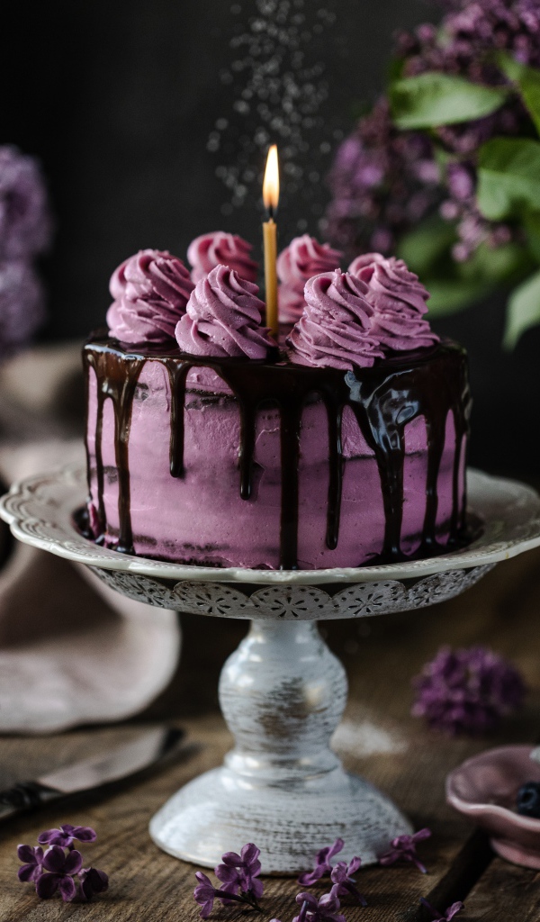 Ягодный торт со свечой на столе с сиренью 