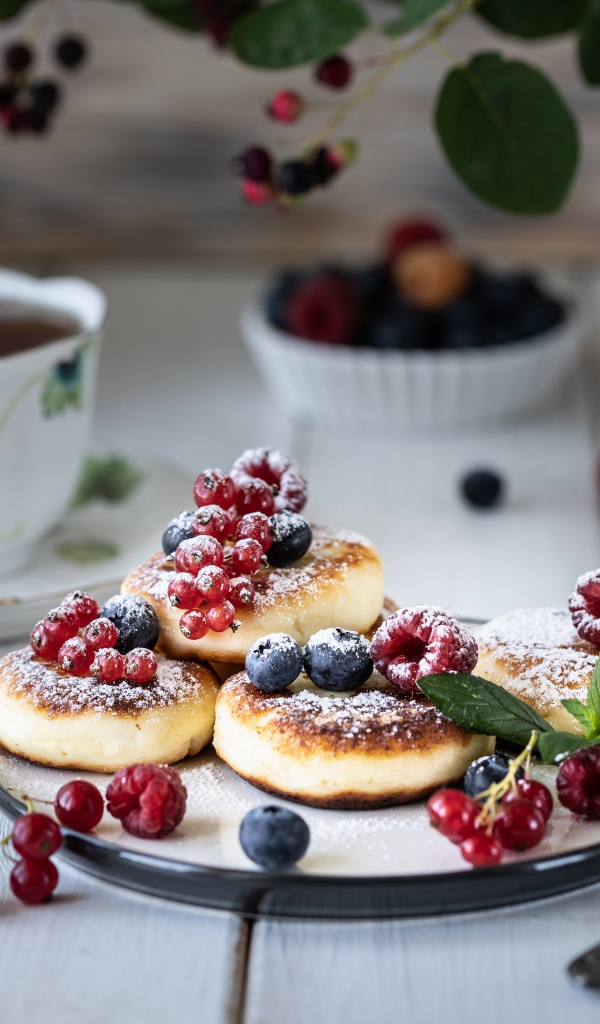 Сырники на столе с ягодами и чаем на завтрак