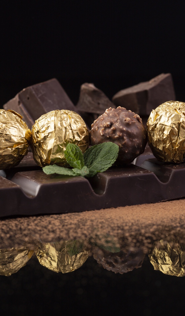 Плитки черного шоколада с конфетами на столе 