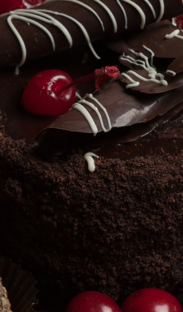 Шоколадный торт с конфетами и вишней на столе 
