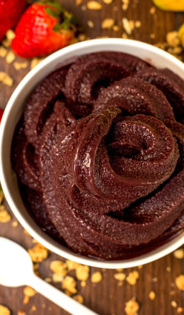 Шоколадная паста на столе с ягодами клубники и бананами