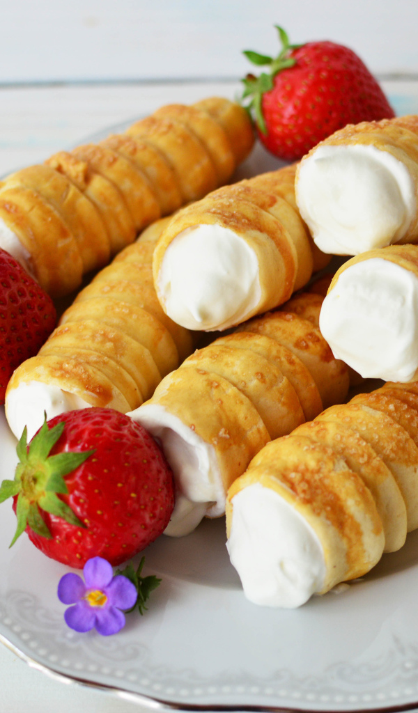 Пирожные с кремом на тарелке с клубникой